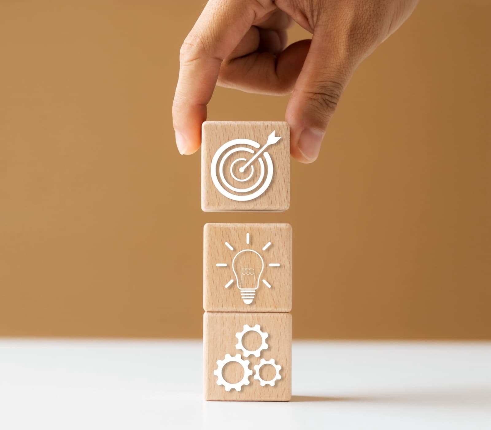 Main empilant des blocs en bois symbolisant objectifs, idées et actions